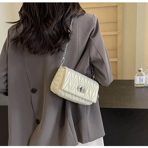 Detailed back view of a white quilted crossbody bag with silver chain and metal twist lock