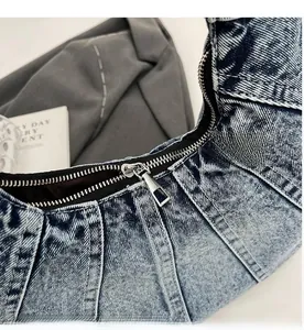 Detailed close-up showing the smooth silver metal zipper on the blue denim shoulder bag