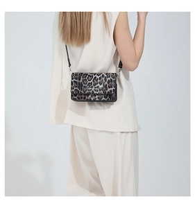 Detail of trendy leopard print rectangular shoulder bag worn over a beige suit outfit