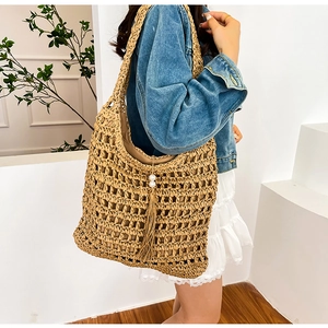 Detailed macro view of hollow straw tote bag with elegant long tassels and pearl charm