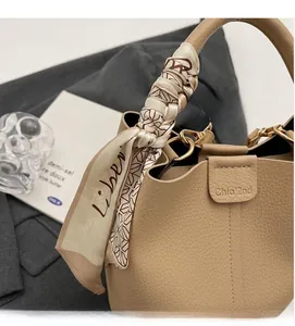 Vue détaillée de la texture du cuir beige et du foulard en soie décoratif sur la poignée