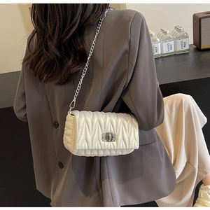Detailed back view of a white quilted crossbody bag with silver chain strap on a model