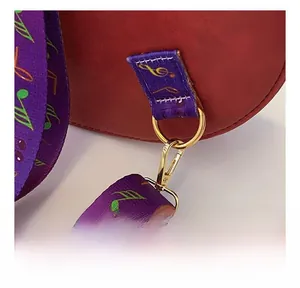 Détail du crochet en métal doré sur sac en cuir rouge avec bandoulière à notes de musique