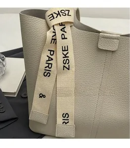 Close-up of beige lychee leather tote with ZSKE PARIS canvas strap and stitched details