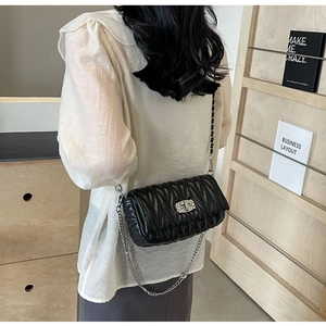 Detail of black quilted leather shoulder bag with silver chain and rhinestone lock