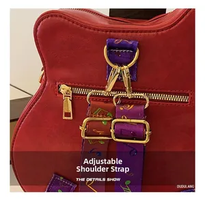 Détail du sac guitare en cuir rouge avec bandoulière à motifs de notes de musique