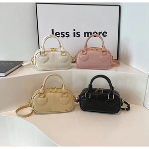 Detail of four faux crocodile leather handbags with heart accents and gold hardware