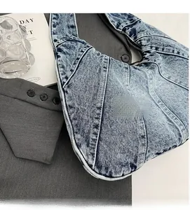 Detailed close-up of light blue denim patchwork shoulder bag with high-quality zipper