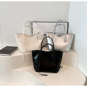 Detailed display of large tote bags in cream, silver, and black with pleated texture