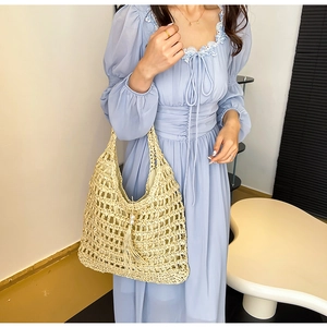 Close-up of straw tote bag showing hollow weave texture and pearl tassel ornament