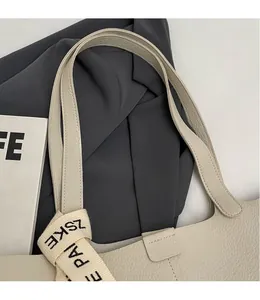 Detail of cream pleated tote bag showing lychee grain leather texture and shoulder straps