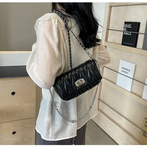 Detail of black quilted shoulder bag featuring sparkling rhinestone buckle and silver chain