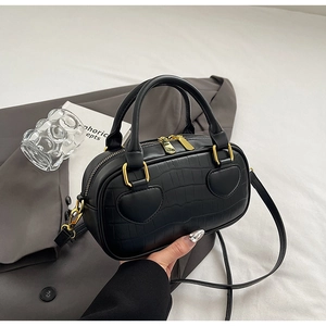 Detail of crocodile embossed black leather bag with gold heart-shaped hardware