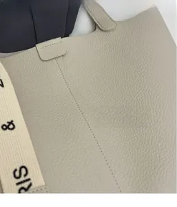 Detailed macro view of beige lychee grain leather tote bag with printed textile strap