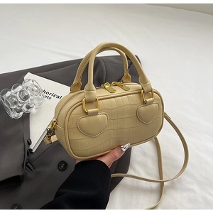 Macro detail of cream crocodile pattern handbag with heart-shaped leather accents