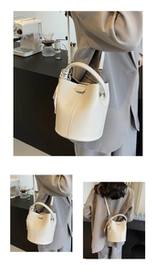 Détail d'un sac seau en cuir crème avec anse en foulard de soie et sangle à logo gravé