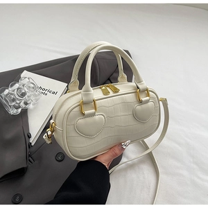Detail of off-white crocodile embossed tote bag with heart patches and gold hardware