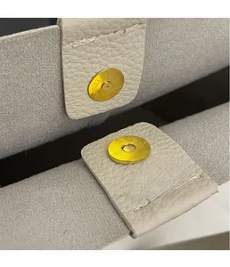 Detailed macro view of the gold magnetic closure on a light grey lychee pattern tote bag