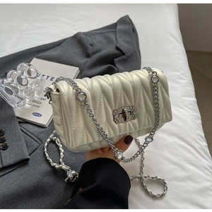 Close-up of pearl white wave-quilted bag with crystal-embellished silver chain strap