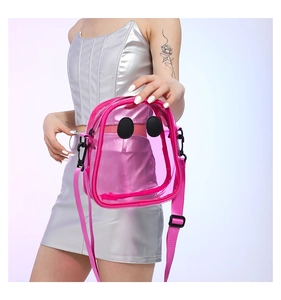 Close-up of pink transparent PVC crossbody bag with black patches and nylon strap