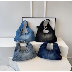 Detail of four denim patchwork crescent bags in light blue, dark blue, and black grey