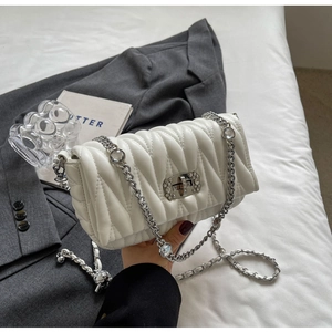 Detail of white quilted crossbody bag with crystal buckle and silver chain strap