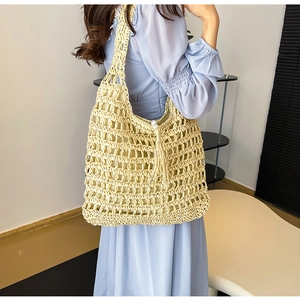 Close-up of beige woven tote bag featuring hollow texture and elegant pearl tassel detail