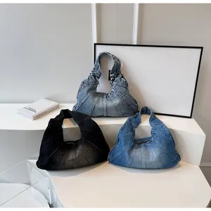 Detailed view of crescent denim shoulder bags in black and blue with vertical stitching
