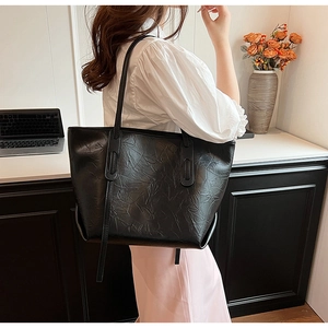 Detail shot of the crinkled vintage leather texture on a large black tote bag