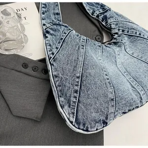 Close-up of patchwork washed denim shoulder bag featuring high-quality stitching and metal zipper