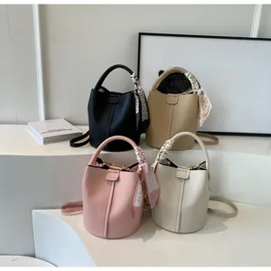Détail de quatre sacs seaux en cuir souple avec d'élégants foulards décoratifs sur la poignée