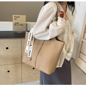 Detail view of beige tote bag made of lychee grain leather with elegant silk ribbon scarf