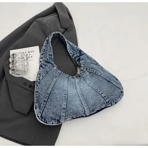 Detail of vintage blue denim hobo bag with patchwork design on a gray suit jacket