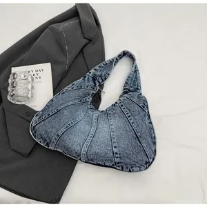 Detail of light wash denim crescent bag with radial patchwork stitching and metal zipper