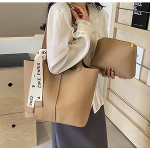 Close-up of stylish tan pebble leather tote bag and matching pouch with logo strap