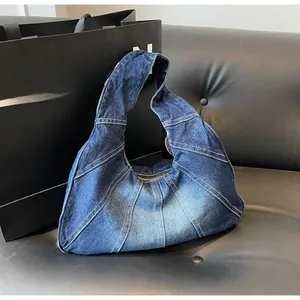 Detail of blue denim hobo bag featuring distressed textures and stitched patchwork design