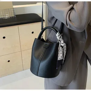 Détail du sac seau en cuir grainé noir avec foulard décoratif et fine bandoulière