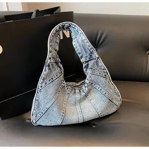 Close-up of vintage washed denim crescent shoulder bag with stitched panels and metal zipper