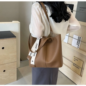 Brown lychee texture bucket tote bag shown on model with decorative ZSKE PARIS ribbon