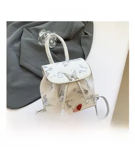 Detail of white backpack with gray butterfly print and metallic butterfly hardware accent