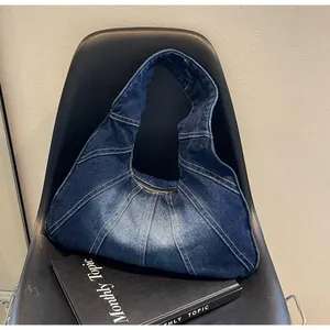 Detailed close-up of retro denim hobo bag with patchwork fabric and washed finish
