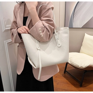 Close-up of beige tote bag with pleated leather texture and slim shoulder straps