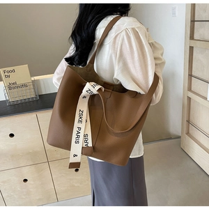 Close-up of brown pebbled leather tote bag with branded ribbon strap detail
