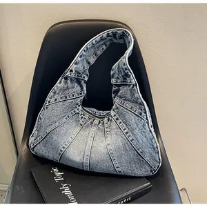 Detail of vintage blue denim patchwork bag with pleated texture and wide shoulder strap