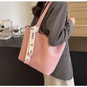 Pink lychee texture tote bag with white printed straps on a grey blazer model