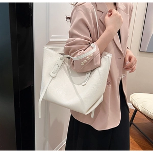 Detail of white pleated texture tote bag worn on shoulder with stylish synthetic leather finish