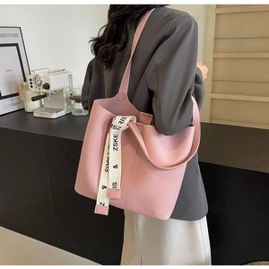Close-up of pink lychee textured tote bag with decorative printed ribbon on shoulder