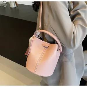 Détail d'un sac seau en cuir rose orné d'un foulard en soie décoratif sur la bandoulière