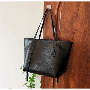 Detail of black tote bag featuring unique pleated texture and dual shoulder straps