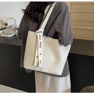 Detailed macro view of the cream white tote bag with lychee texture and decorative strap